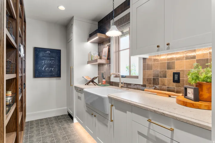 Built-in wood shelving, overhead recessed lighting, built-in white cabinetry, farmhouse sink, and square tile backsplash