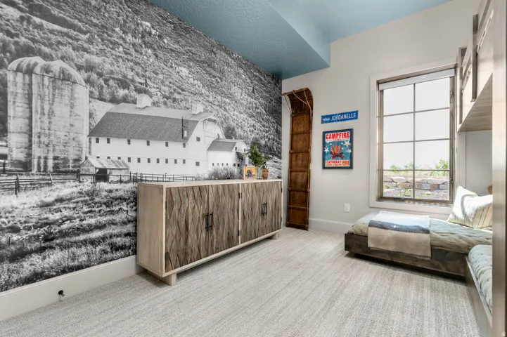 Textured accent wall, light-toned carpeting, built-in window seat, large multi-pane window, and a built-in storage unit