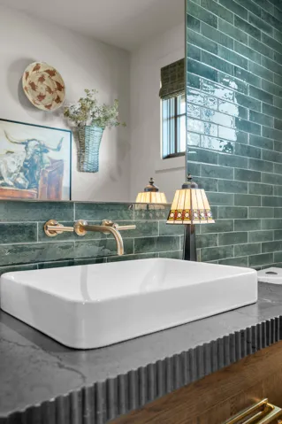 Rectangular vessel sink atop a textured gray countertop, featuring a wall-mounted brass faucet
