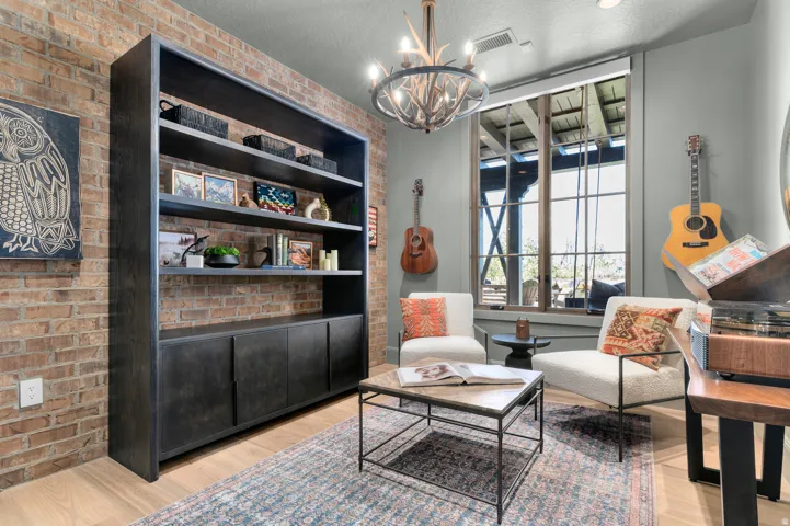 Exposed brick accent wall, wood-finish flooring, built-in shelving with lower cabinetry, and a large window with transom detailing