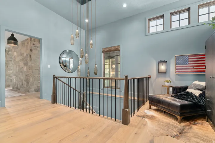 Hardwood flooring throughout, custom chandelier, three transom windows, wrought iron stair railing, and a stone accent wall