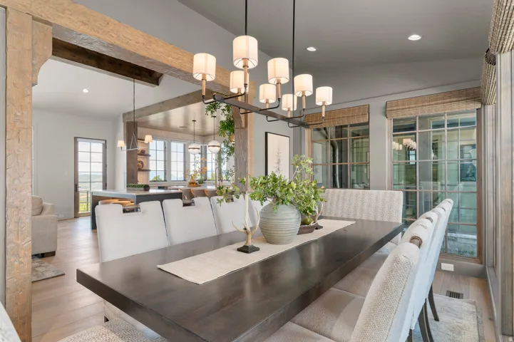 Formal dining area with a linear chandelier, wood-finish flooring, and exposed wood beam accents