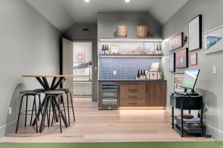 Hardwood-style flooring throughout, built-in cabinetry with integrated wine refrigeration, open shelving with accent lighting, and a textured backsplash