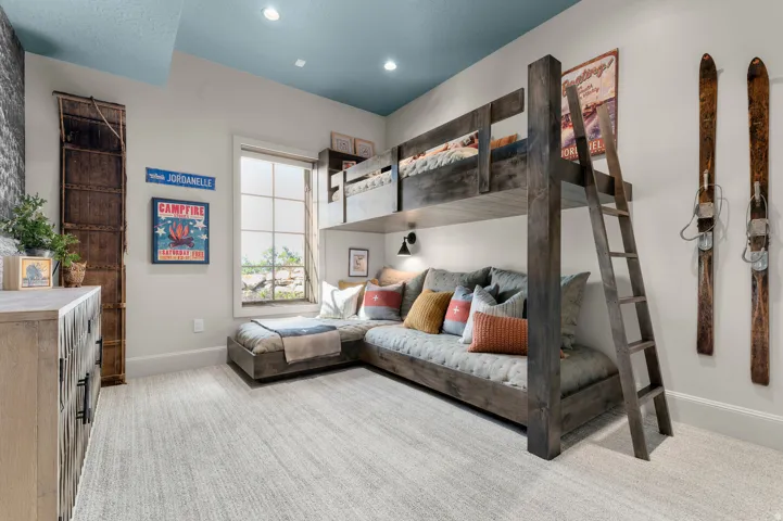 Built-in bunk bed with ladder, recessed lighting, wall-mounted sconce, and multi-pane window