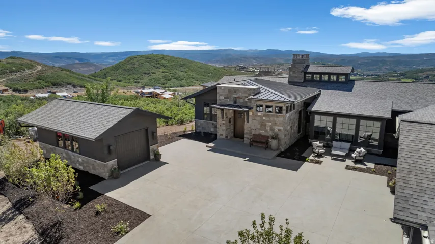 Expansive driveway with stone and dark-toned siding on the main residence and detached garage