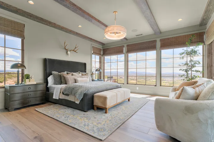 Wood-finish flooring, exposed ceiling beams, recessed lighting, large picture windows, and a central chandelier