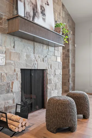 Stone-clad fireplace with a built-in firebox, featuring a wood-finish mantel and wood-finish flooring