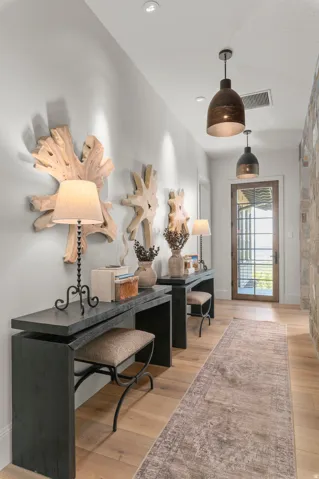 Recessed ceiling lighting, wood-finish flooring, stone accent wall, ceiling-mounted pendant lights, and a full-light panel door