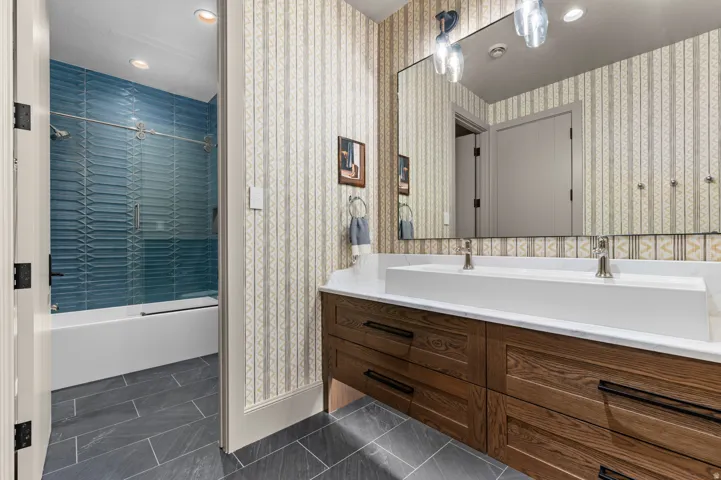 Dual vanity with integrated rectangular sinks, wood-finish cabinetry, and a large wall-mounted mirror