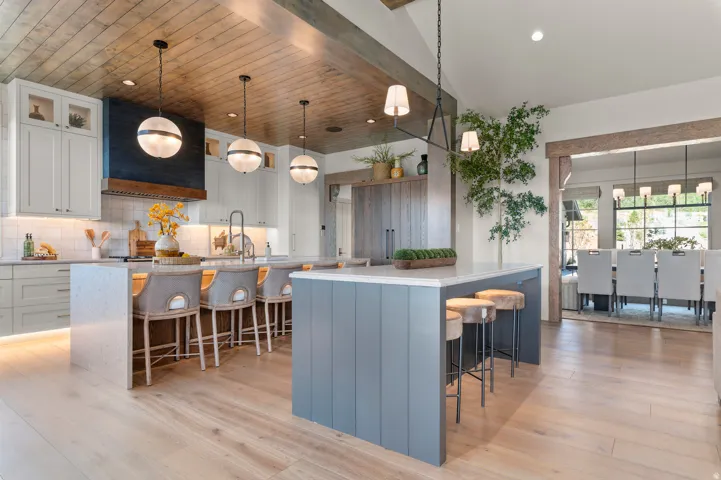 Gourmet kitchen featuring a wood-panel ceiling, light wood-finish flooring, two kitchen islands, and a custom range hood