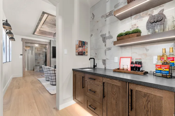 Built-in wet bar featuring dark wood-finish cabinetry, a dark countertop, and a matte black faucet