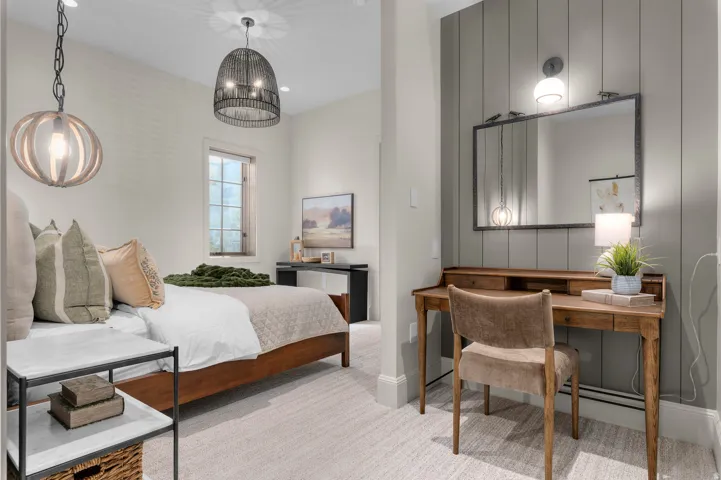 Dual pendant light fixtures, window with gridded panes, built-in desk with mirror, and carpeted flooring
