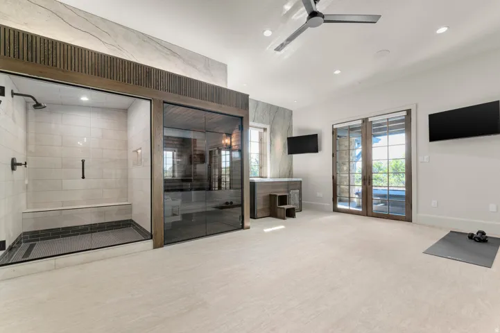Expansive glass-enclosed shower with a built-in bench and hexagonal tile flooring