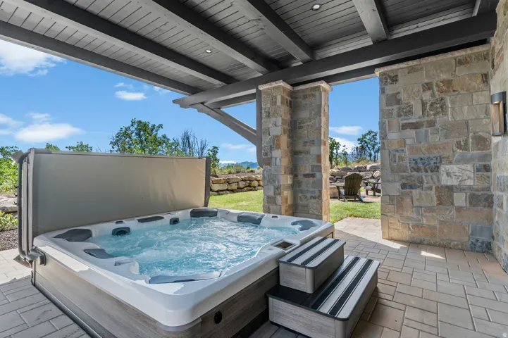 Outdoor hot tub with integrated steps, set on a stone paver patio