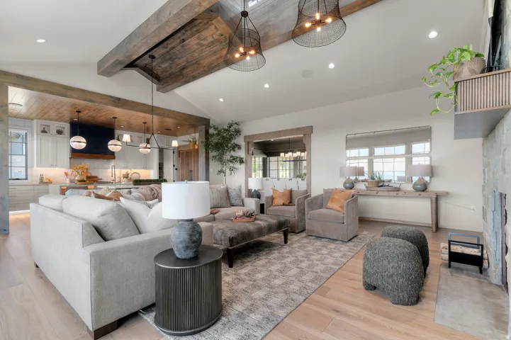Vaulted ceiling with exposed wood beams, wood-finish flooring, recessed lighting, and a stone-clad fireplace