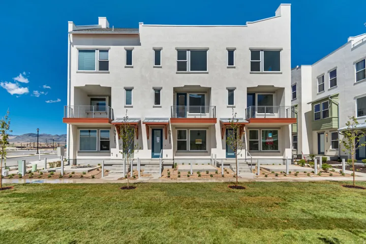 Contemporary facade with stucco exterior, multiple balconies featuring metal railings, and a manicured lawn