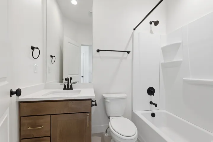 White vanity with wood-finish cabinetry, white countertop, and matte black fixtures