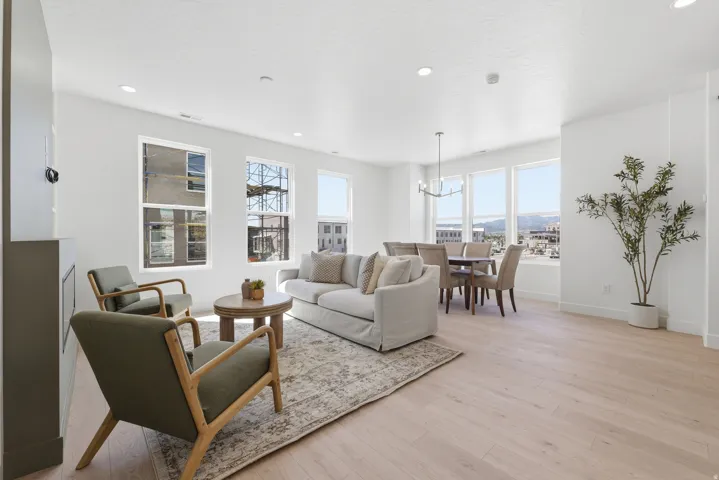 Open-concept living area featuring light wood-finish flooring, recessed lighting, and multiple large windows