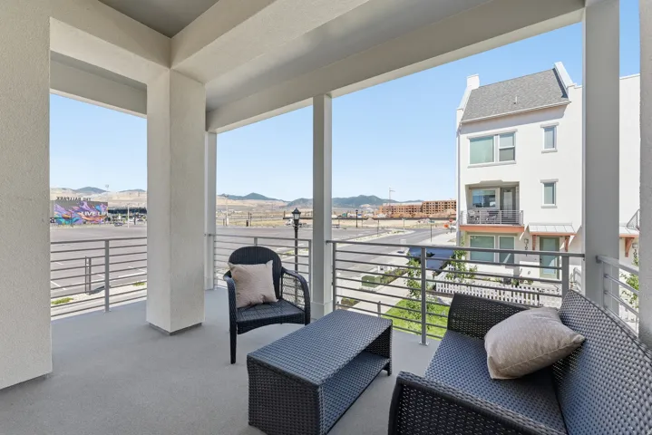 Expansive outdoor balcony with textured concrete flooring, sturdy support columns, and horizontal metal railings