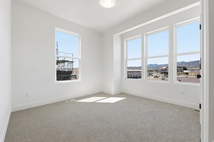 Bright room with light-colored carpeting, white walls, and a single ceiling-mounted light fixture