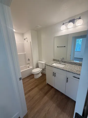 White vanity with a speckled countertop, undermount sink, and black hardware