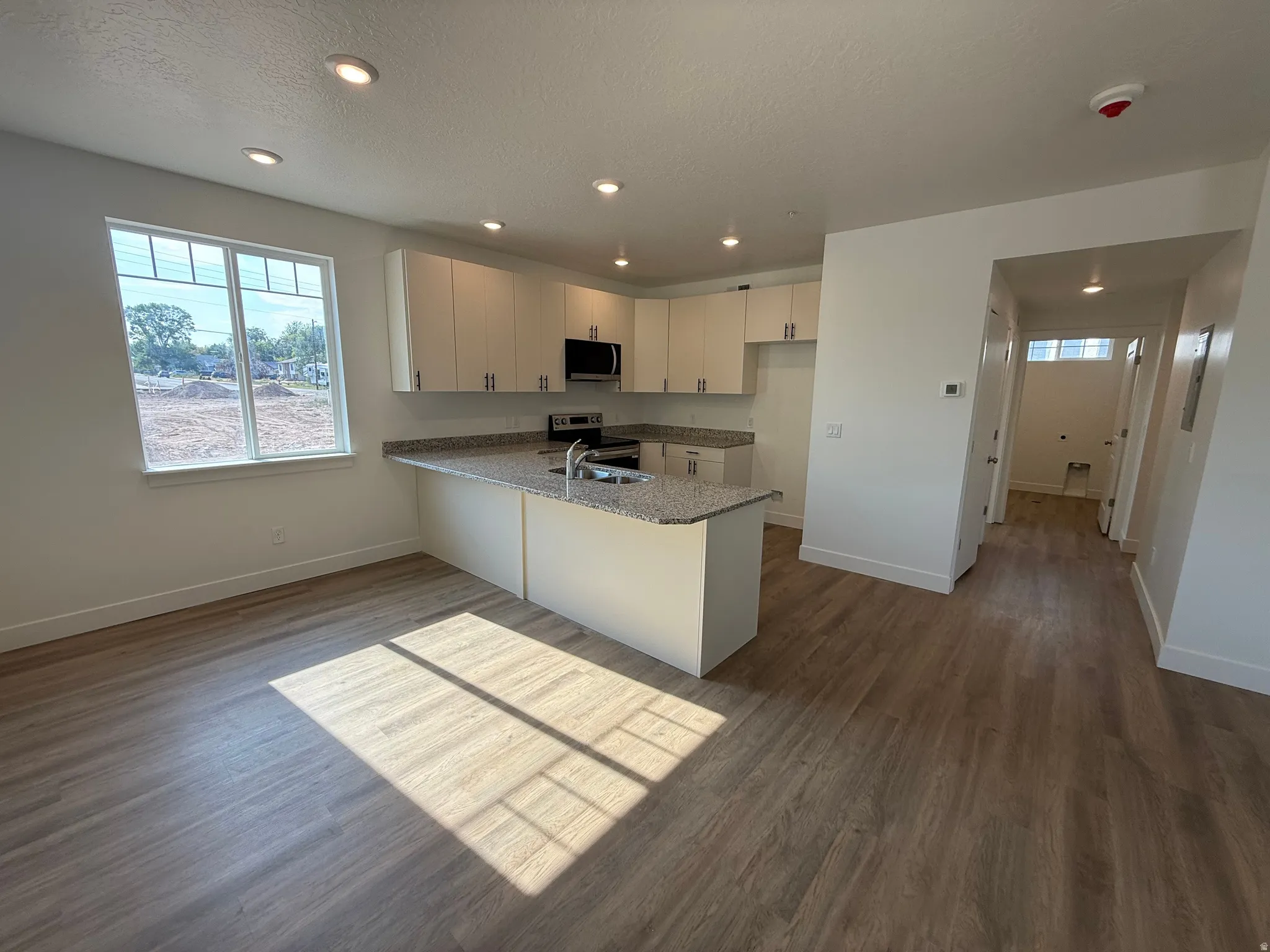 Modern kitchen with white cabinetry, granite-style countertops, stainless-steel appliances, and wood-finish flooring