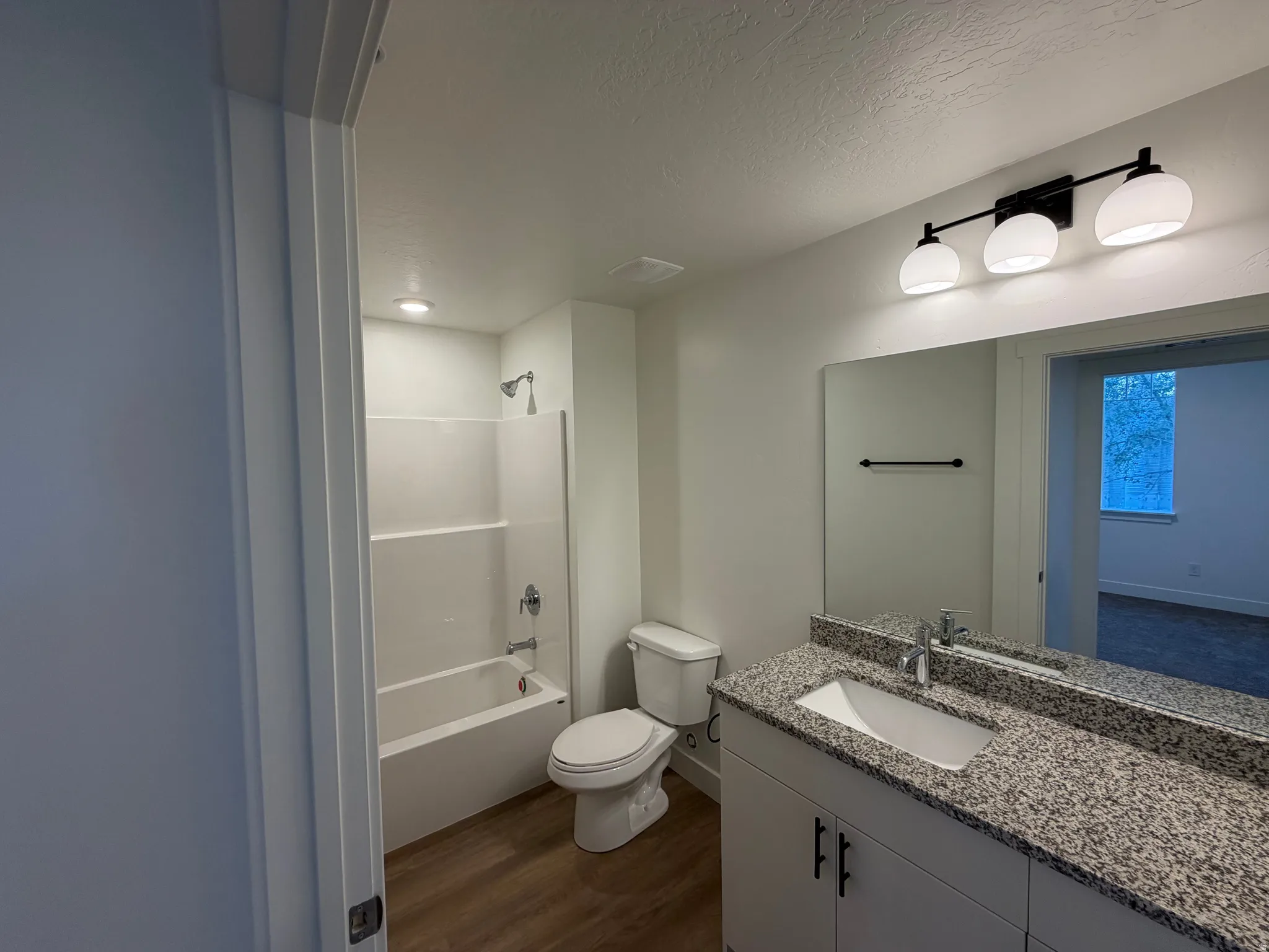 Bathroom featuring a white vanity with a stone-finish countertop, undermount sink, and a large mirror
