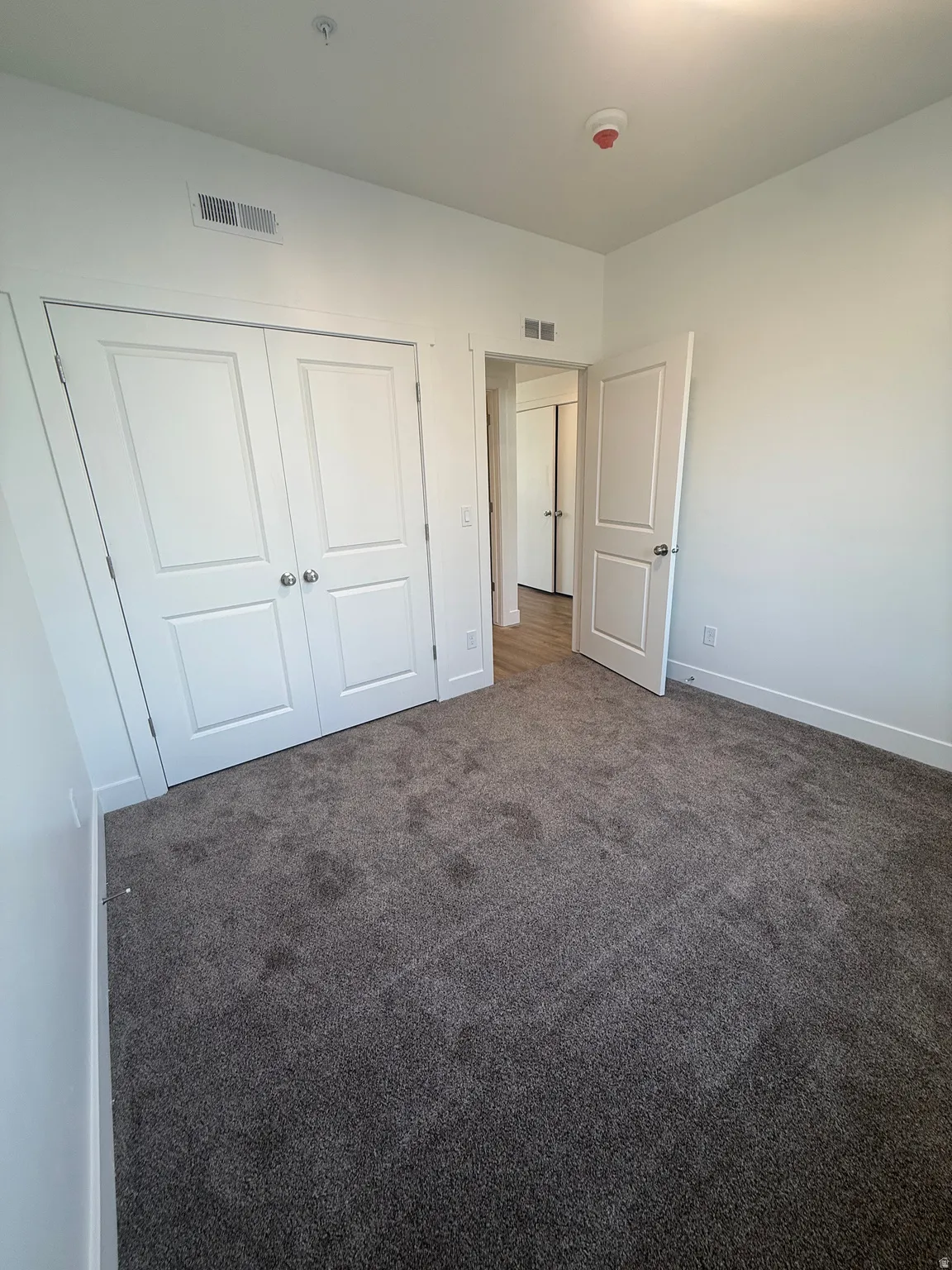 Neutral wall paint, recessed lighting, wall-to-wall carpeting, white interior doors, and a closet with bifold doors