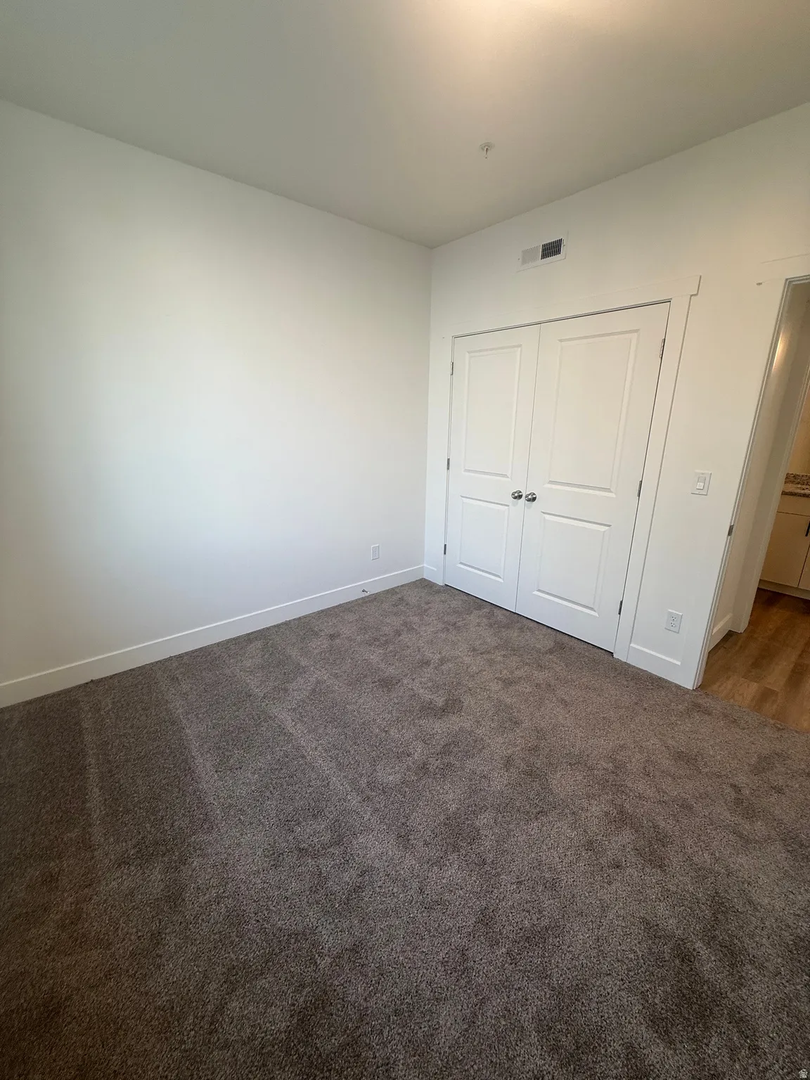 Plush carpeting, recessed ceiling lighting, and a bi-fold closet door with contemporary hardware