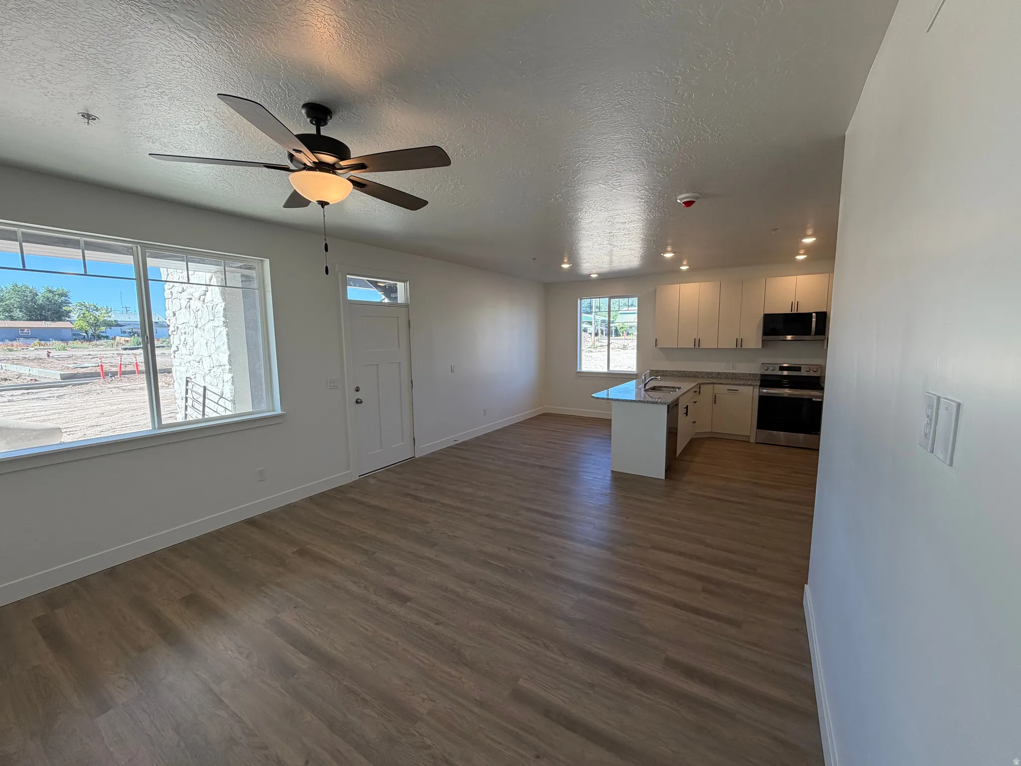 Open-concept living space with wood-finish flooring, a ceiling fan, and white trim