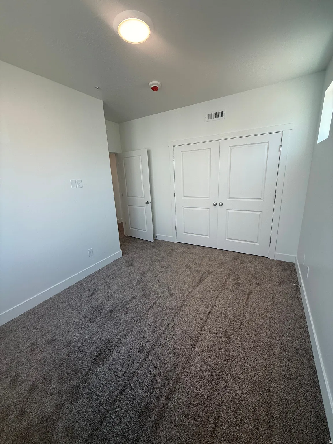 Plush carpet flooring, neutral wall tones, interior door, and bi-fold closet doors