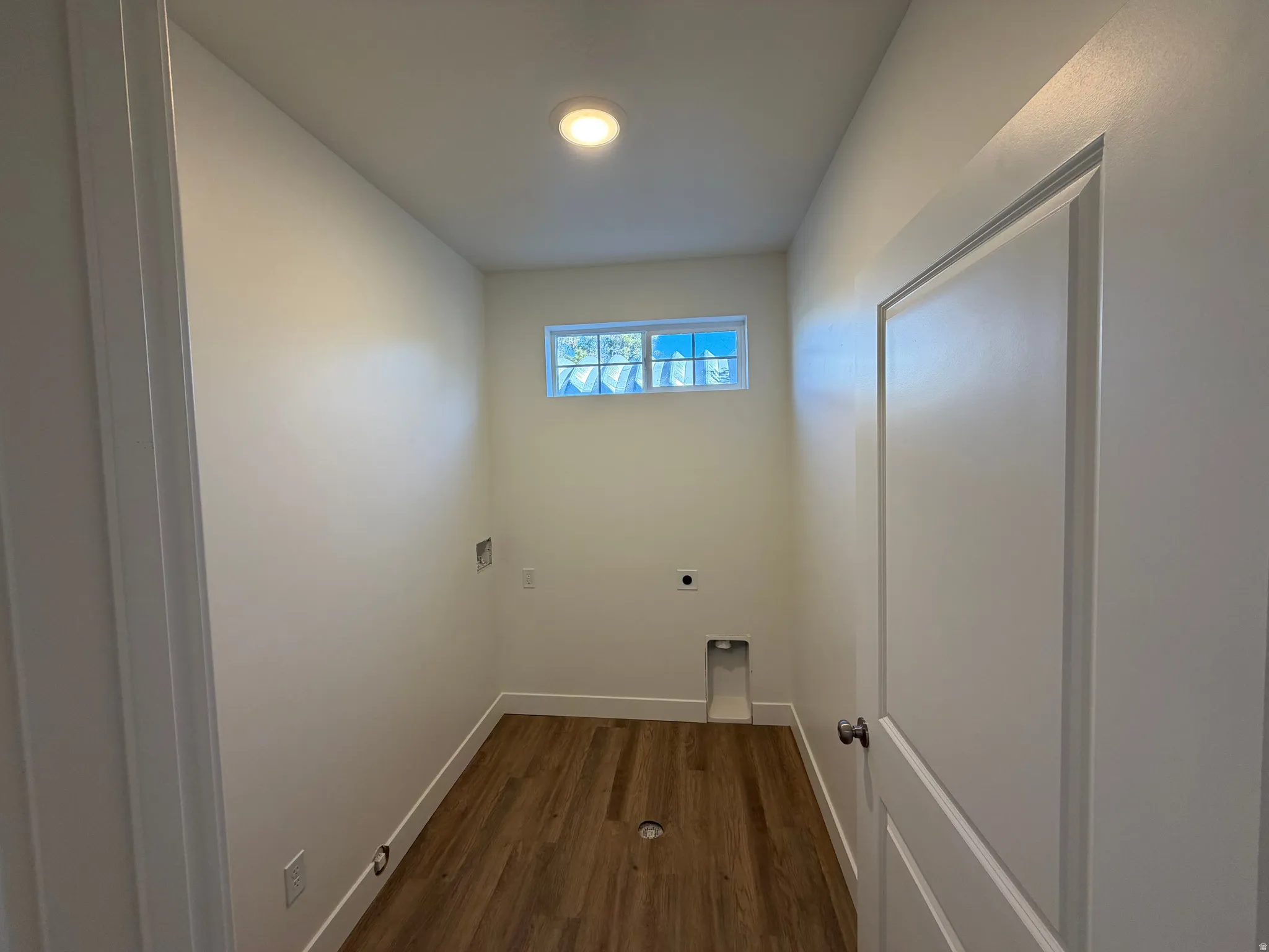 Recessed ceiling lighting, wood-finish flooring, white trim, and a window with privacy glass