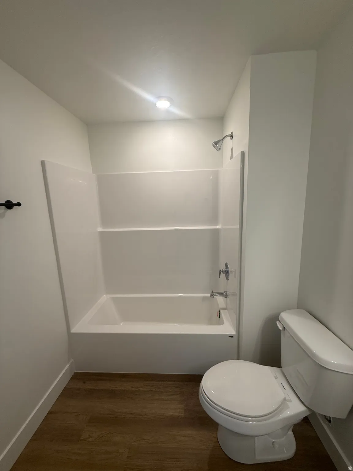 Tub/shower combination with chrome fixtures and wood-finish flooring