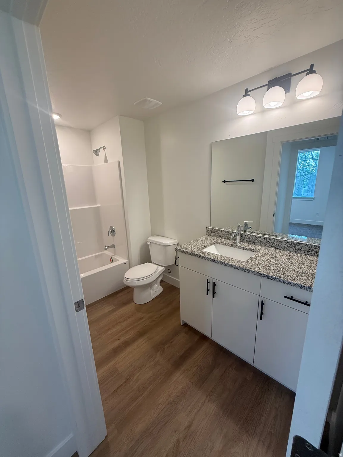 White vanity with a speckled countertop, undermount sink, and black hardware
