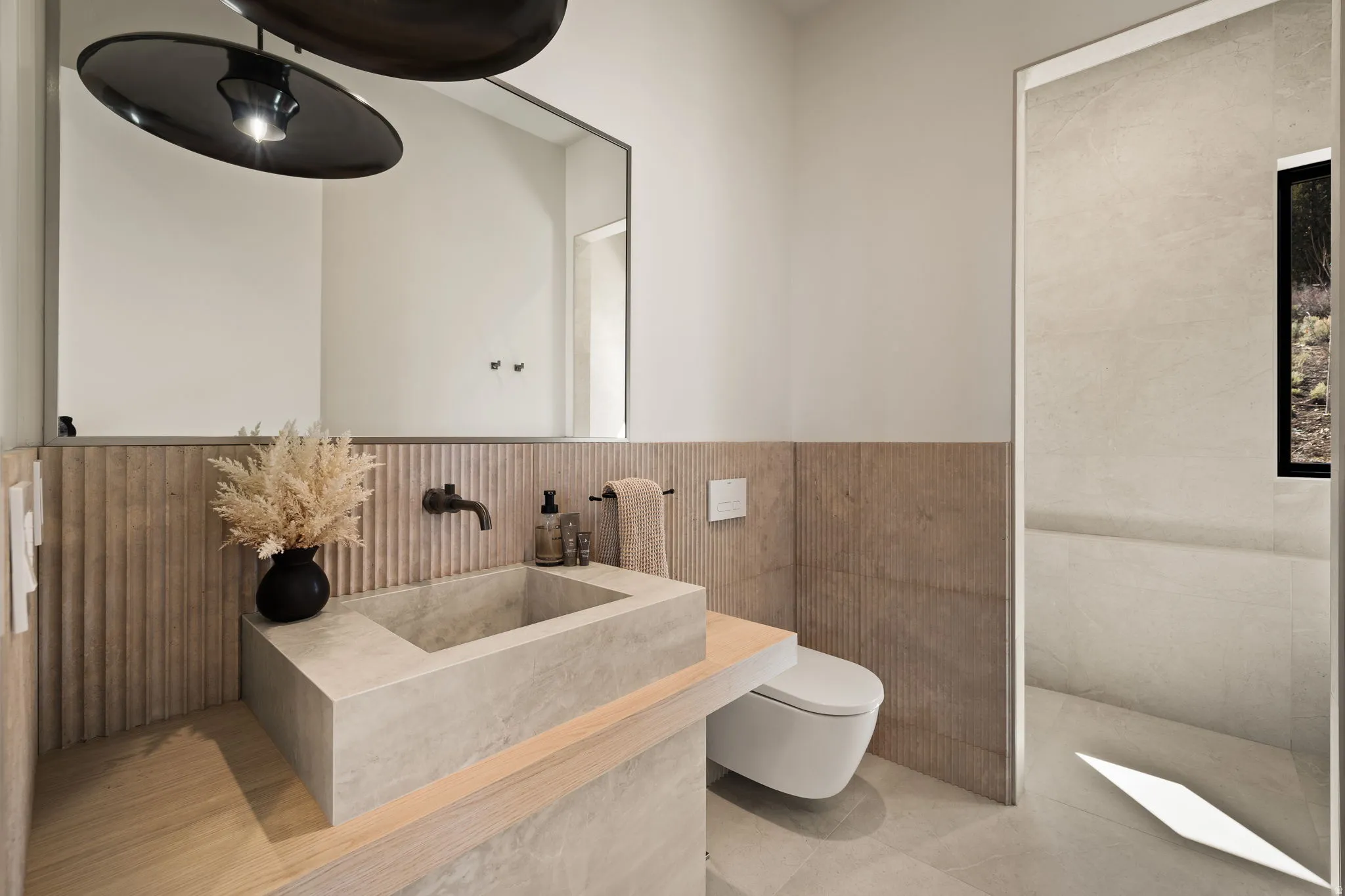 Floating concrete basin with a wall-mounted faucet, full-width vanity mirror, and textured wall paneling