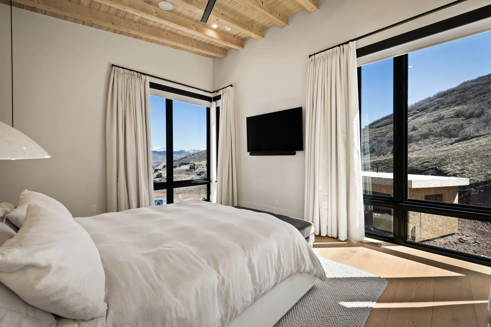 Exposed wood-beam ceiling, wood-finish flooring, and large picture windows