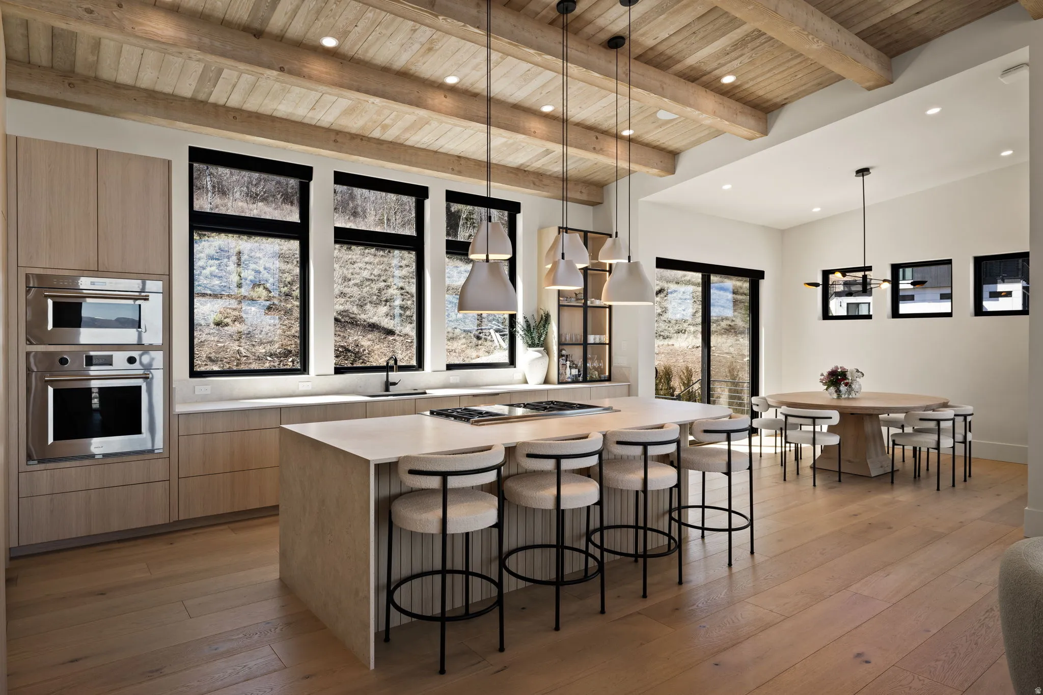 Kitchen featuring a large central island, integrated stainless steel appliances, wood-finish flooring, exposed beam ceiling, and ample natural light