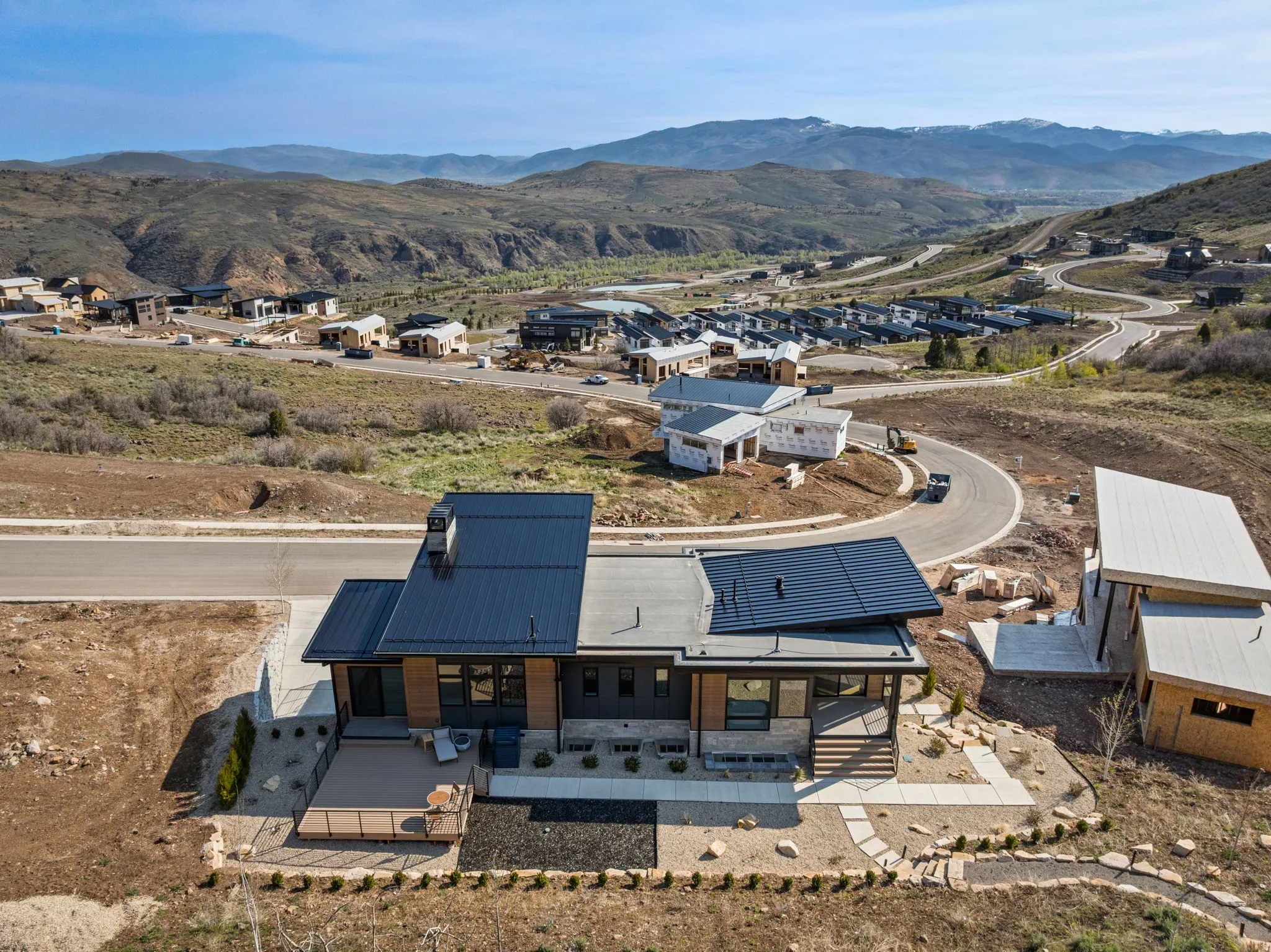 Modern architectural design with a dark metal roof and light flat roof sections