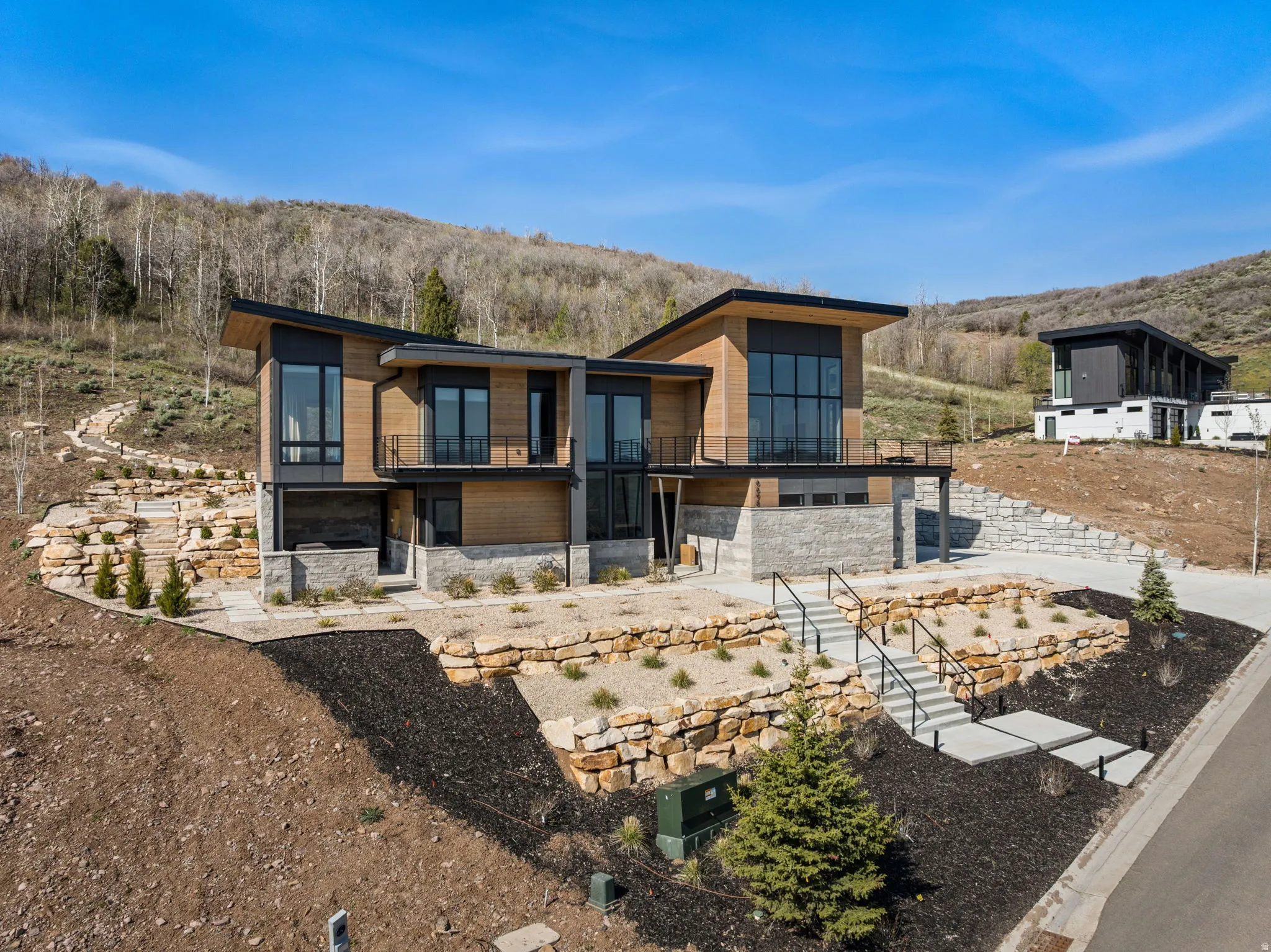 Modern architectural design featuring expansive glass panels, wood-finish siding, and stone accents