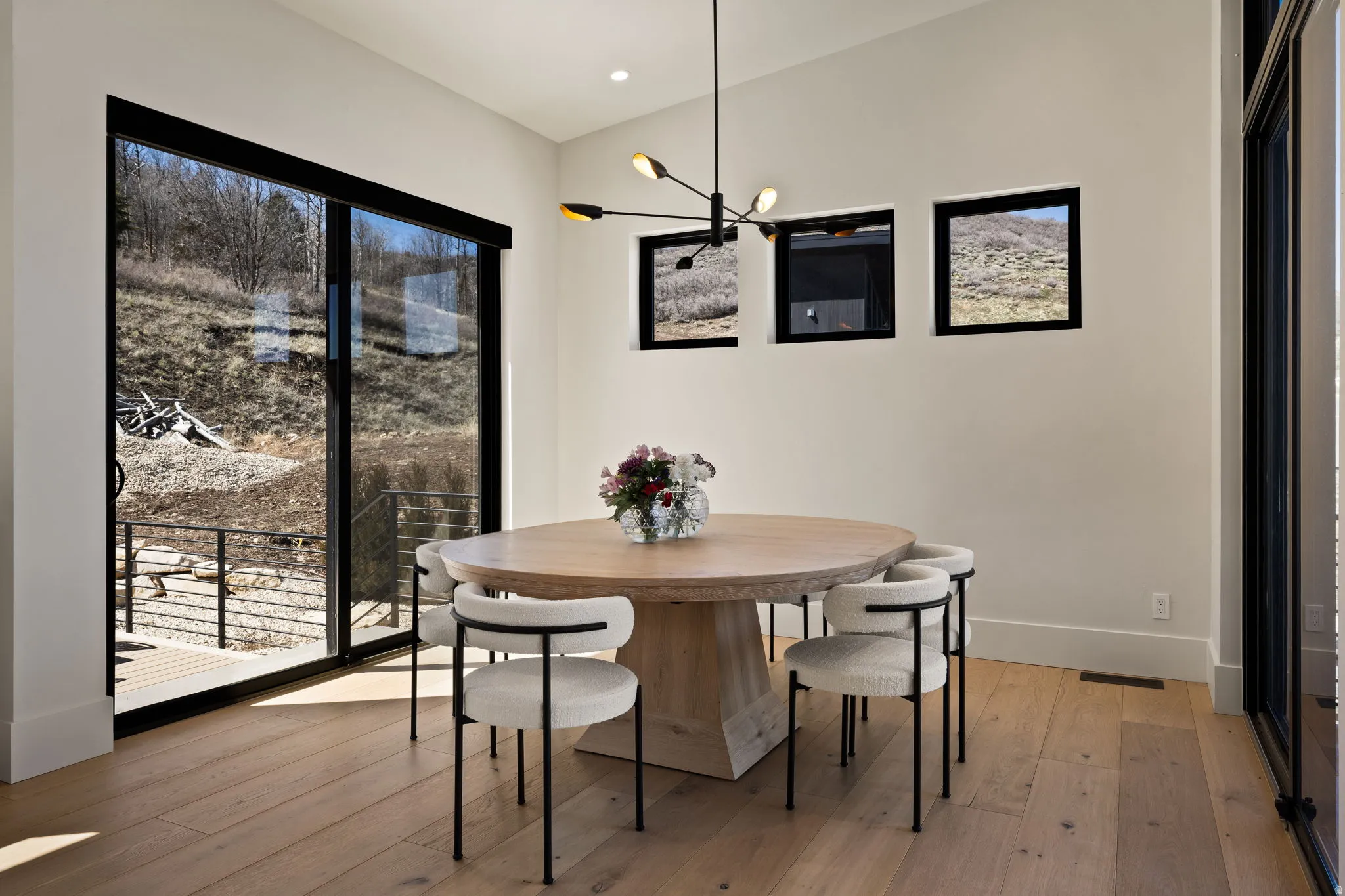 Wide-plank wood-finish flooring, white walls, black-framed sliding glass door, and recessed lighting