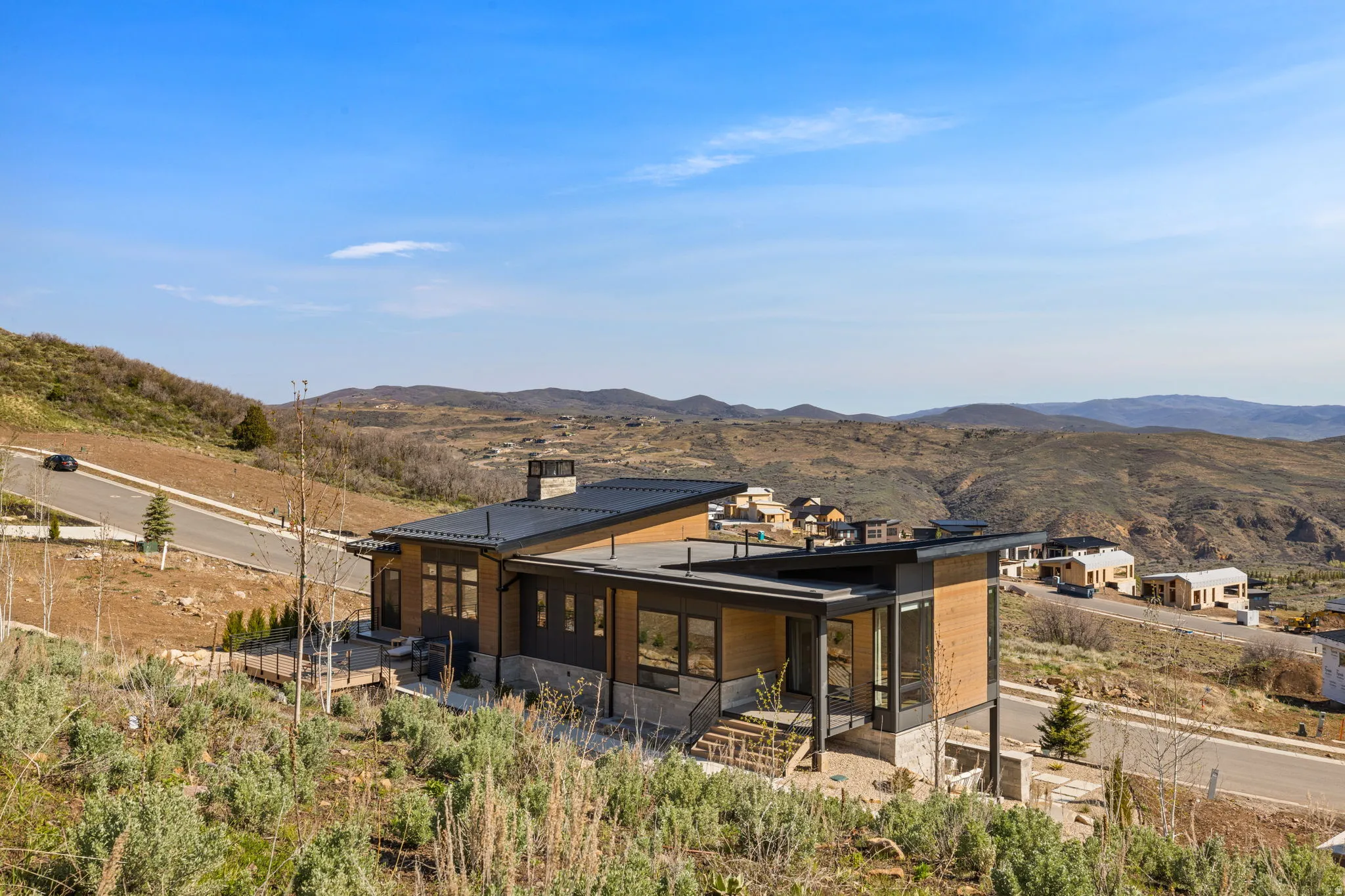 Modern architecture featuring a low-slope roof, expansive windows, and a stone chimney