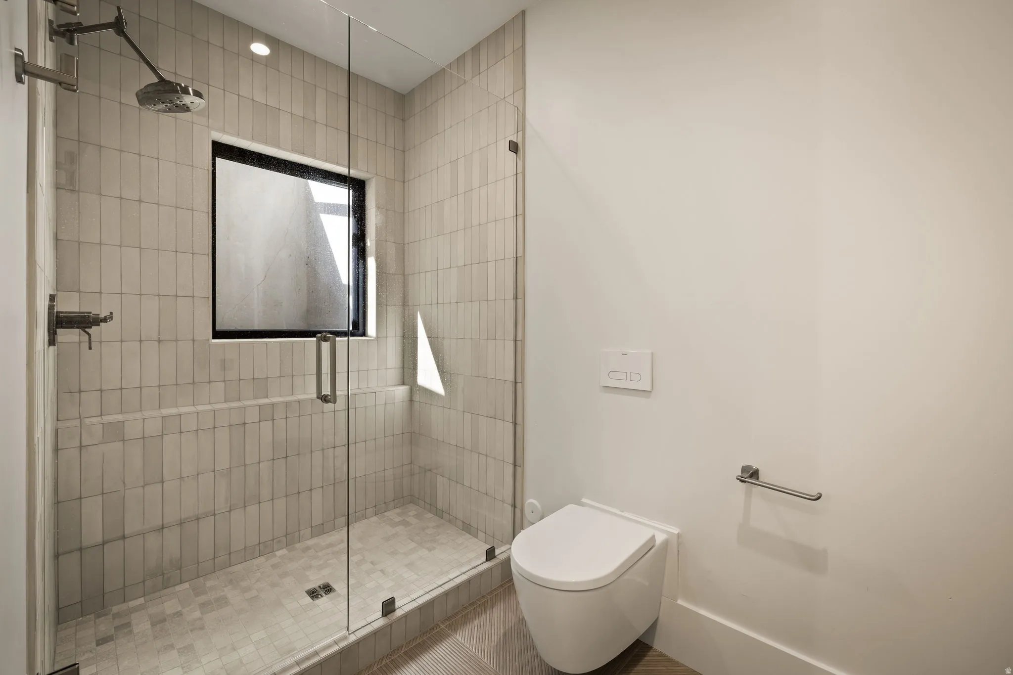 Glass-enclosed shower with vertical tile surround and integrated window