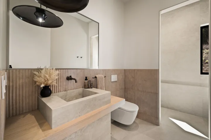 Floating concrete basin with a wall-mounted faucet, full-width vanity mirror, and textured wall paneling