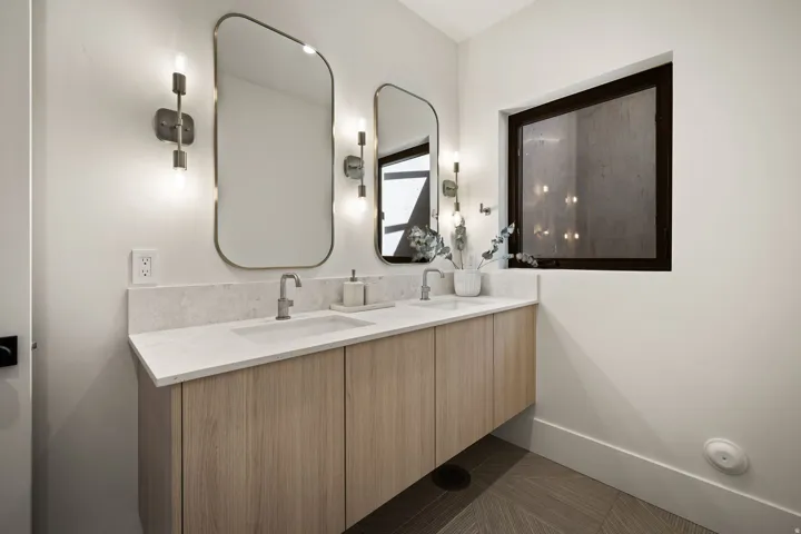 Floating double vanity with light wood-finish cabinetry, dual rectangular undermount sinks, and light-toned countertop