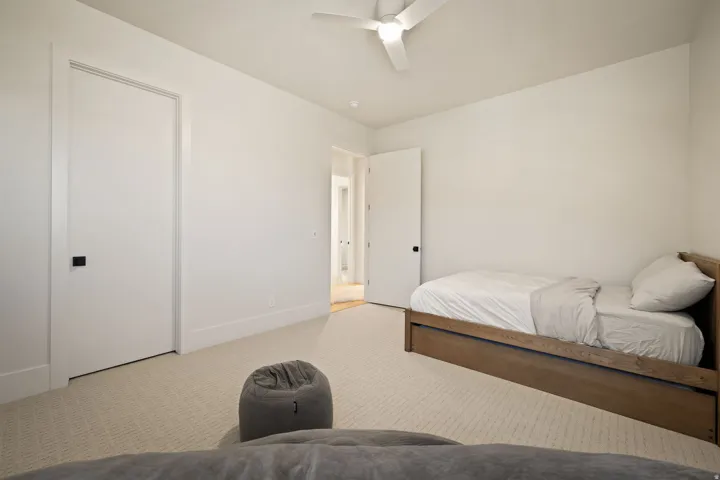 Light-colored carpeting, white walls, and a modern ceiling fan with integrated lighting