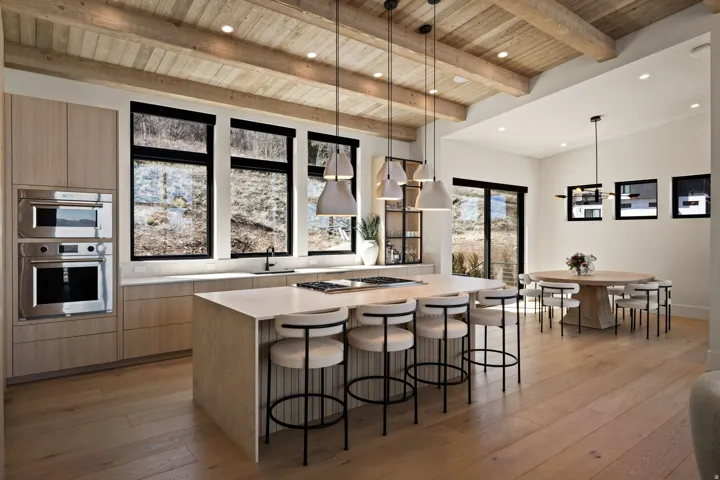 Kitchen featuring a large central island, integrated stainless steel appliances, wood-finish flooring, exposed beam ceiling, and ample natural light