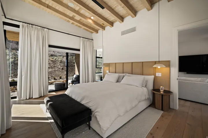 Vaulted wood-plank ceiling, wood-finish flooring, full-height glass doors, and integrated wall paneling