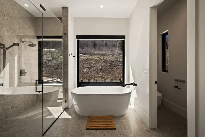 Freestanding soaking tub, large format tile flooring, glass-enclosed shower with dual shower heads, and an additional built-in tub