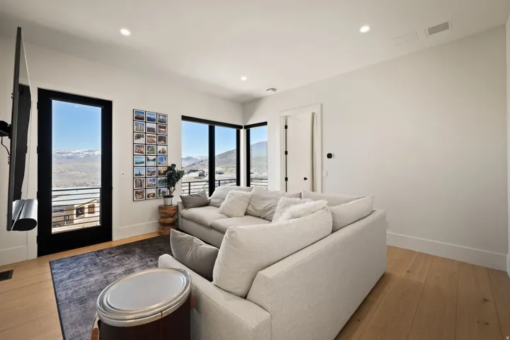 Expansive windows, wood-finish flooring, recessed lighting, and a white interior door