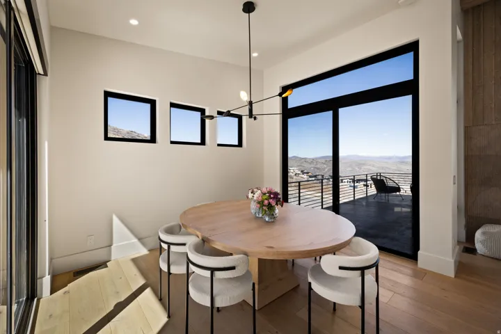 Expansive glass sliding door, light wood-finish flooring, recessed lighting, and a modern chandelier